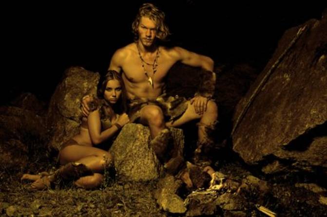 Первобытный человек и его женщина, сидя у костра в пещере — стоковое фото